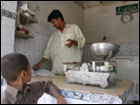 Zahid Husain helps a customer at his brother Shahid's milk shop in Hijrat Colony, Karachi