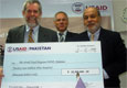 USAID Pakistan Deputy Mission Director Joseph Williams presenting a token check to the WFP Director of Operations, Ramiro Lopes Da Silva, at the signing ceremony of an agreement to help ease Pakistan’s food crisis.