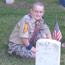 Boy Scout placing a flag at a grave site.