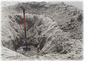 Photo of a large hole dug at the beach showing an example of the water table, below which all the soil is saturated with water. 