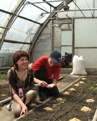 Masha, a disabled student, tends to seedlings with a fellow student at a greenhouse.