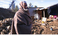 Mumtaz Alisha, a village elder salvages items from rubble to add to his new shelter home - Click to read this story