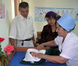 Janubek Mansurov and his wife Farida watch as a nurse examines their daughter.