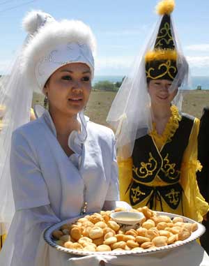 A Kyrgyz girl in traditional attire offers tourists snacks near Ysyk Kol lake, Kyrgyzstan, May 18, 2006. [© AP Images]