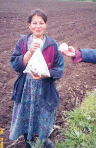 Photo: Orphan shows off onion harvest which was produced with the help of USAID’s Farmer to Farmer volunteer Dave Pearce.