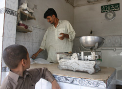 Zahid Husain, right, serves a customer at his brother Shahid’s milk shop in Hijrat Colony, Karachi.