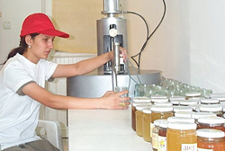 An association member bottles honey in jars sterilized with equipment purchased with a USAID grant.