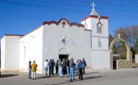 A group of people stand outside a historic church in Dona Ana, New Mexico