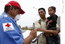 A Red Cross volunteer wearing a surgical mask asks questions to Guatemalan Jose Antonio Miranda at the Guatemala-Mexico border crossing in Tecun Uman, Guatemala, 28 April 2009