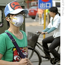 A local resident wearing a facemask walks along a street in Beijing, 29 Apr 2009