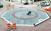 Photo: a mason working on a large mosaic in a street intersection