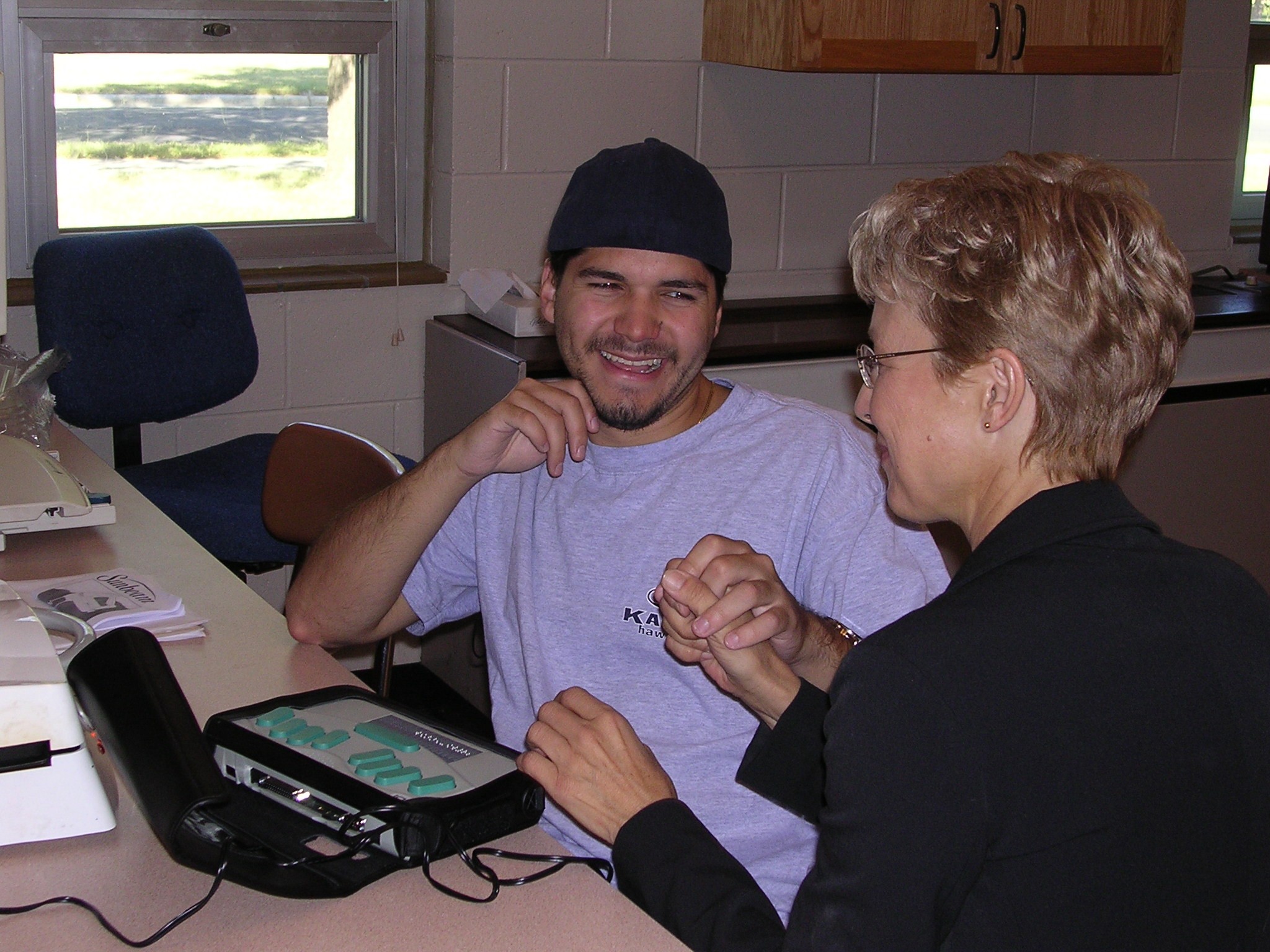 DeafBlind student learning BrailleNote machine communicates with MCB Training Center instructor via tactile sign language