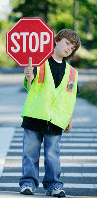 Click to open page with information for parents and educators. Photo a child holding a stop sign, directing traffic by a school crossing