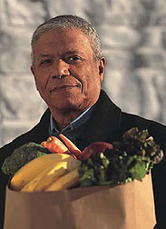 Photo: Older man carrying a bag of fruits and vegetables.