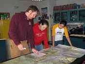 Nate Olson, biologist at the Selawik NWR, helps two Selawik students plot the winter movements of Western Arctic caribou, April 2006.  Photo by Susan Georgette.