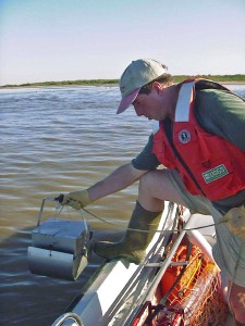 USGS scientist measuring pH and other water properties on the banks of Fourmile Creek, Iowa, before collecting a sediment sample for laboratory biodegradation experiments.