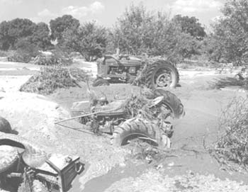 Tractors covered by sand, 
             mud, and debris in the wake of the flood near Lawrence (photo courtesy of U.S. 
           Department of Agriculture, Natural Resources Conservation Service, Lawrence)