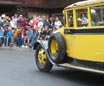 A Yellow Bus pulls up in front of a crowd at Old Faithful Inn