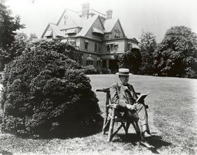 Thomas Edison sitting in front of Glenmont reading a book.