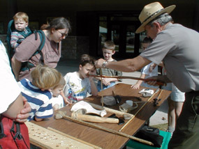 Ranger demonstrating ancient American Indian tools to kids