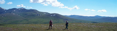 Two hikers in the open ridgeline tundra of Alaska.