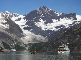 boat with kayaker in front of mountain