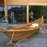 A bateau sits in front of the glass facade of the Marinus Willett visitor center, beached to unload its cargo in a display about trade on the Mohawk River