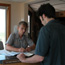 Park ranger shows map and permit forms to man in front of information desk.