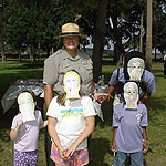 Children wearing masks made during a program pose with a ranger.