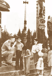 Photo of doctor examining Alaskan children near totem poles