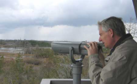 National Wildlife Refuge Chief Bill Hartwig peers through a spotting scope during a fire management tour at Georgia's Okefenokee National Wildlife Refuge. The refuge is home to one of the nation's only all-volunteer landowner associations, which includes private, commercial and government interests. (USFWS)