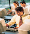 A man working at a computer in a classroom setting.