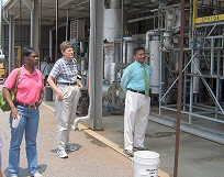 Picture of three people viewing a pilot size processing facility for converting poultry litter to bio-oil.