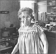 Photo of an elderly woman standing in her kitchen.