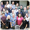 A large group of people dressed in civilian clothes stand in a open patio area looking up for the photograph.