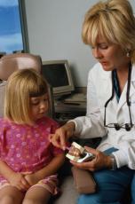 Photograph of a female dentist showing a young girl proper tooth brushing techniques