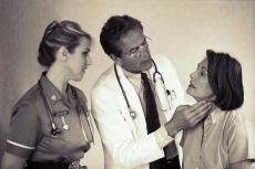 Photograph of a male doctor and female nurse examing a female patient