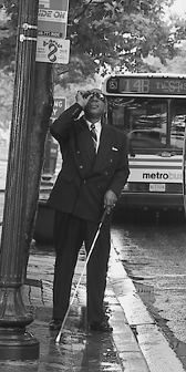 Un hombre que tiene baja visión y que usa un bastón blanco usa un lente monocular para leer la información del autobús.