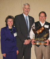 Photograph: Jim Clarr (right) accepting the Lloyd Swift, Sr Award. Presented by Anne Zimmermann, USFS/WFW Director (far left). Joel Holtrop (US Forest Service Deputy Chief for NFS; far left) was a congratulator.