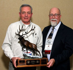 Photograph: Mark Henjum accepting and holding the elk country award statue (left), posing with Tom Toman (RMEF).