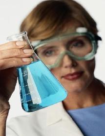 Female Scientist examines a beaker of blue liquid.