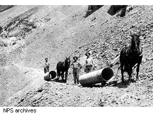 Workers drag drainage pipes by horseback in 1927 during construction of the road west of Logan Pass.