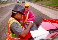 Photo of two people using a laptop to collect data at a highway construction site