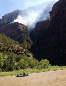 Rafters floating on Green River below fire on nearby butte.