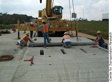 TxDOT had nearly 340 precast panels fabricated and installed on the frontage road near I-35 in Georgetown, TX, as part of a demonstration project in 2002. Here, workers guide a partialwidth precast panel into place.