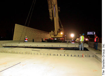 The speed of placement of the precast panels used in the California demonstration improved significantly over the 2 nights of construction. Here, a crane lowers another panel into place.