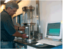 A technician runs the Simple Performance Tester to  evaluate an asphalt mixture for its response to permanent deformation (rutting) and fatigue cracking.