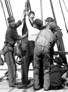 Sailors hauling on a line aboard a ship.