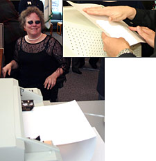 Photo of Kim Driver sitting near the Braille printer