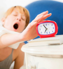 Photo of a sleepy woman reaching for her alarm clock 